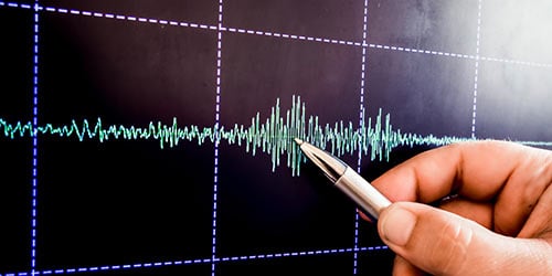 Hand pointing to graph of vibration waves.