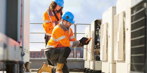 Photo of two technicians working on rooftop HVAC unit.