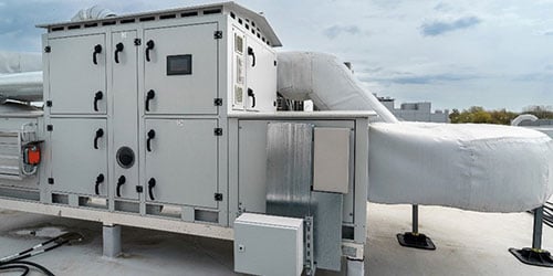Rooftop HVAC unit with cloudy sky in background.